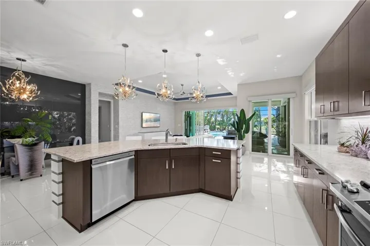 Kitchen featuring stove, a notable chandelier, a sink, dishwasher, and dark brown cabinetry