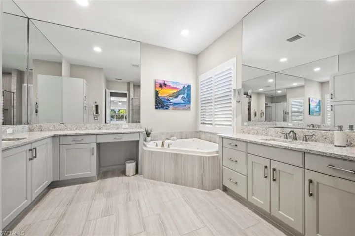 Full bathroom with a shower stall, a sink, visible vents, two vanities, and a bath