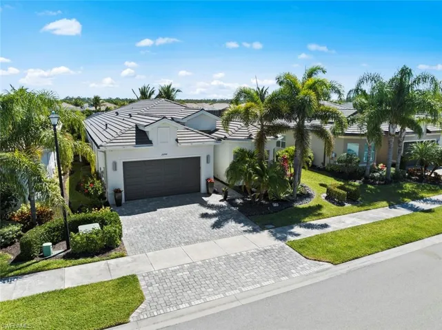 View of front facade with a tile roof, stucco siding, an attached garage, decorative driveway, and a front yard