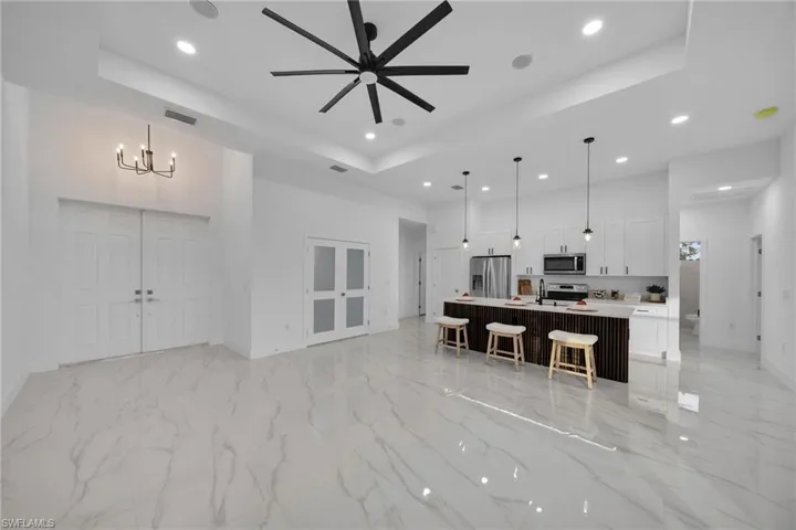 Virtually Staging Kitchen featuring white cabinetry, appliances with stainless steel finishes, pendant lighting, and a center island with sink