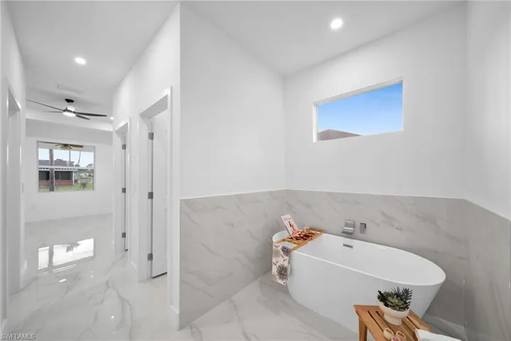 Bathroom with a bathing tub, tile walls, and ceiling fan