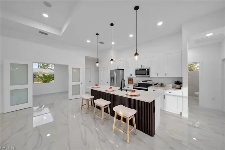 Virtually Staging Kitchen with a kitchen island with sink, appliances with stainless steel finishes, a wealth of natural light, and white cabinetry