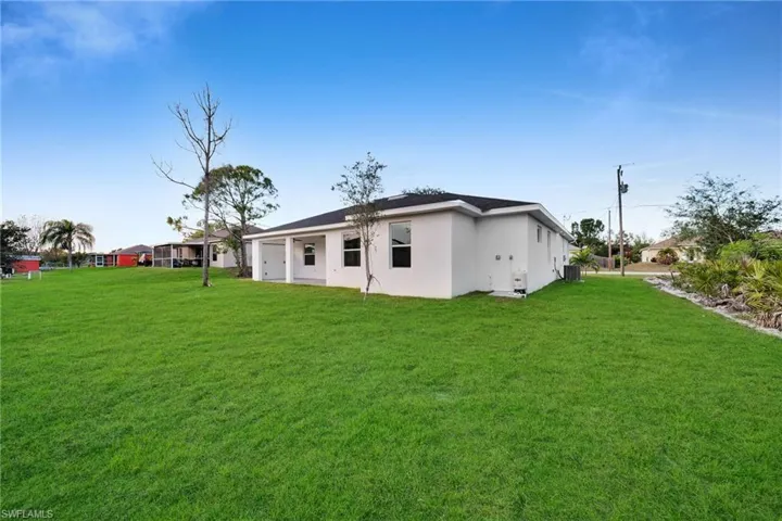 Back of property with cooling unit and a yard