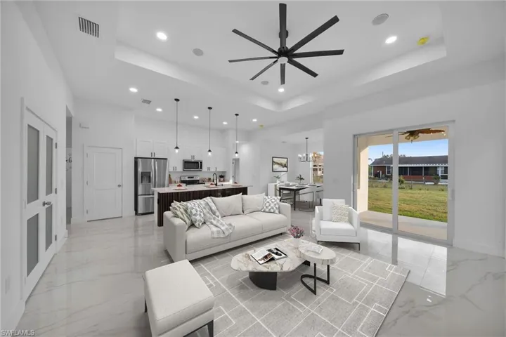 Virtually Staging Living room with ceiling fan with notable chandelier, a raised ceiling, and sink