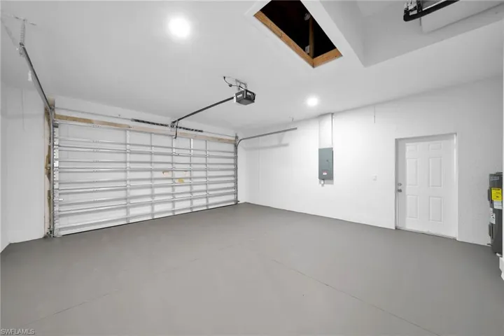 Garage featuring a garage door opener and electric panel
