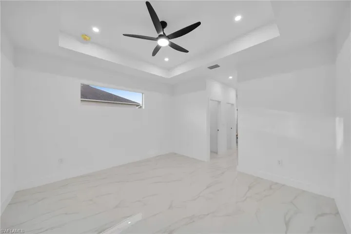 Unfurnished room featuring a raised ceiling and ceiling fan