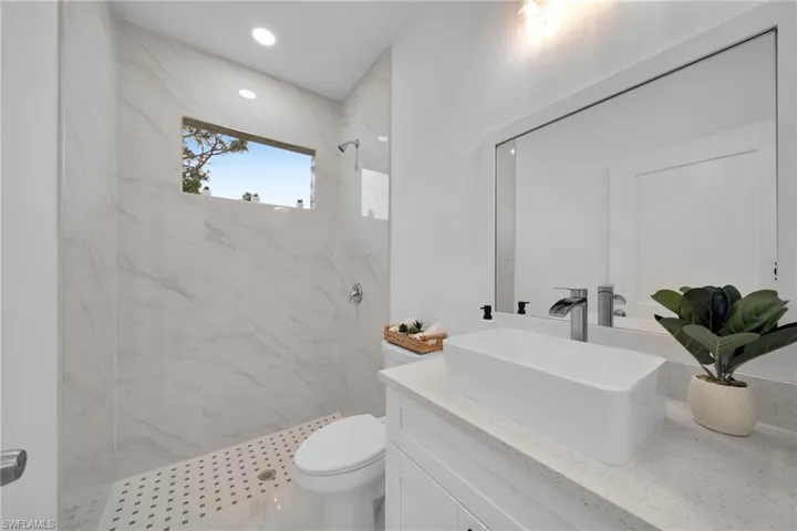 Bathroom featuring toilet, vanity, and a tile shower