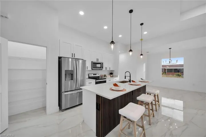 Virtually Staging Kitchen with white cabinetry, an island with sink, appliances with stainless steel finishes, a breakfast bar, and sink