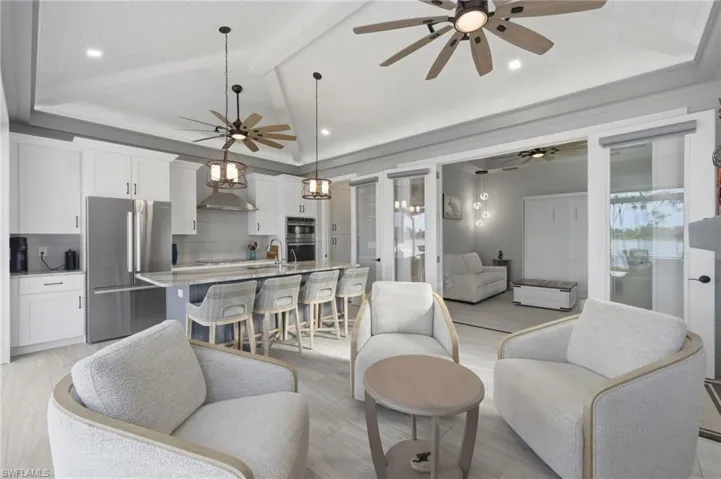 Living room featuring light wood finished floors, recessed lighting, ceiling fan, and beam ceiling