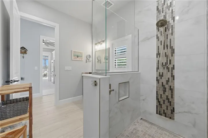 Full bath featuring a walk in shower, healthy amount of natural light, a ceiling fan, and light wood-style floors