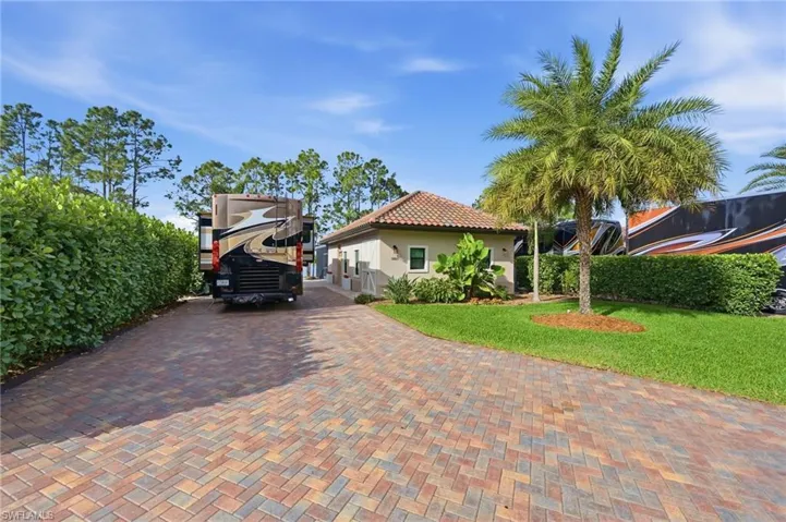 View of front facade featuring a front lawn, stucco siding, a tile roof, and decorative driveway