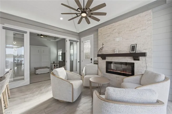 Living room with ceiling fan, a fireplace, wood finish floors, and wood walls