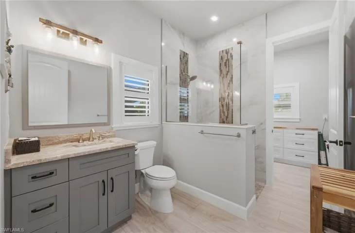 Bathroom with vanity and a marble finish shower