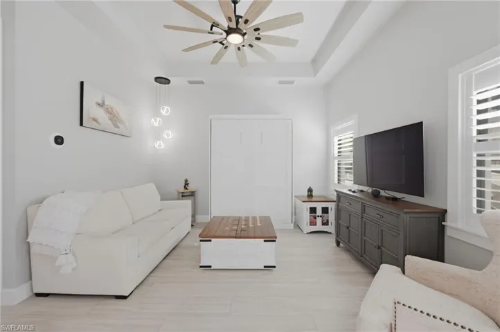 Living room with a tray ceiling and a ceiling fan