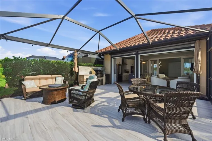 Wooden deck with a lanai, outdoor lounge area, a sunroom, and exterior kitchen
