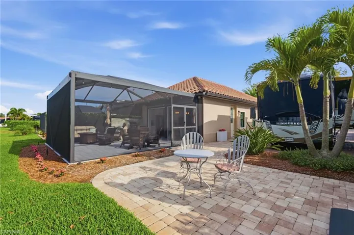 Rear view of property with a patio, glass enclosure, a sunroom, stucco siding, and a lawn