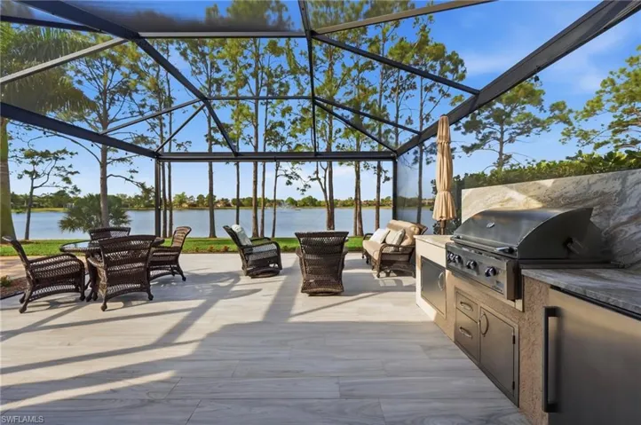 View of patio / terrace with a lanai, an outdoor kitchen / dining area, and a water view