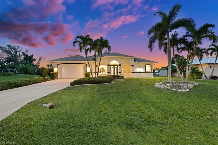View of front of home with a garage and a yard