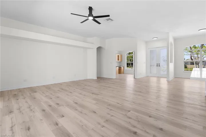 Unfurnished living room featuring ceiling fan, light hardwood / wood-style flooring, and french doors