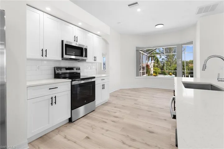 Kitchen featuring light hardwood / wood-style floors, stainless steel appliances, backsplash, sink, and white cabinetry