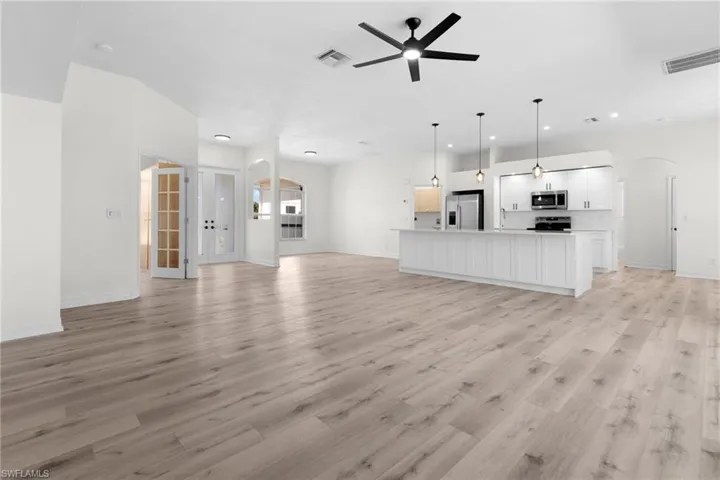 Unfurnished living room with sink, ceiling fan, and light hardwood / wood-style flooring