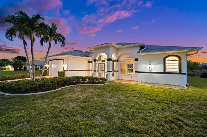 View of front facade featuring a garage and a yard
