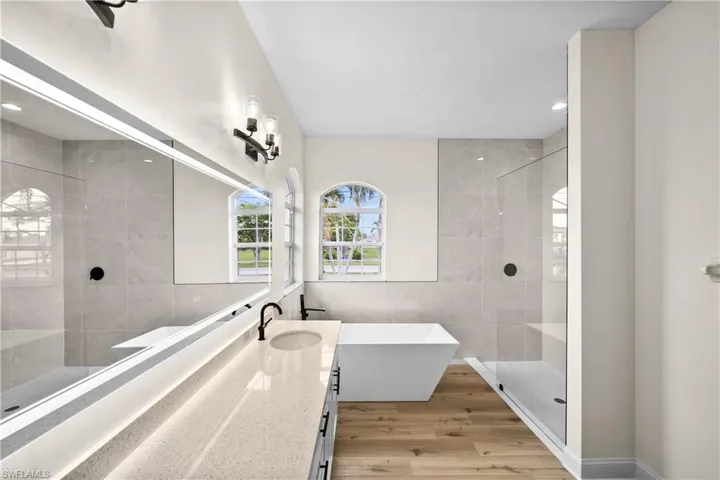 Bathroom with vanity, an enclosed shower, tile walls, and hardwood / wood-style floors