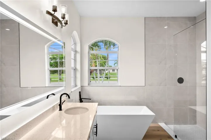 Bathroom featuring hardwood / wood-style flooring, tile walls, a shower with shower door, and vanity
