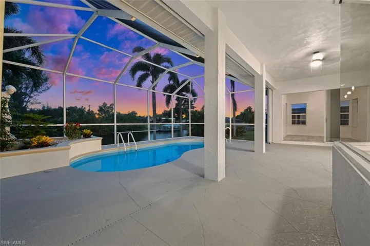 Pool at dusk with a patio area and a lanai