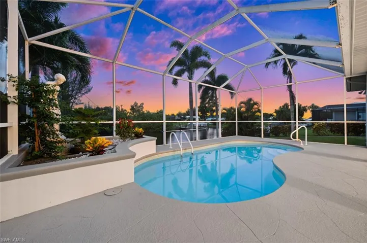 Pool at dusk with a patio area and a lanai