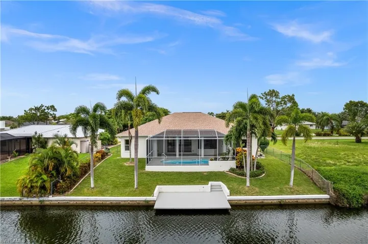 Back of property with a lanai, a water view, and a yard