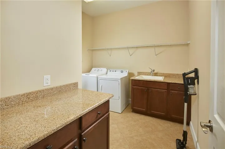 Spacious laundry room with laundry sink and additional storage space.