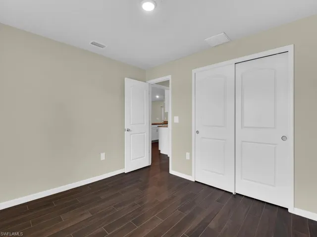 Unfurnished bedroom featuring dark wood-type flooring and a closet