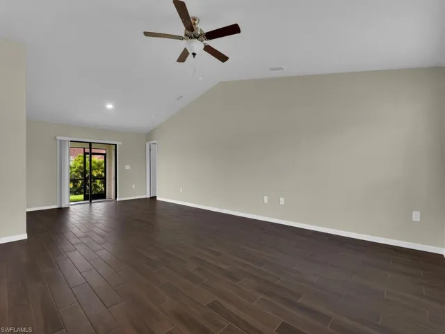 Unfurnished living room featuring dark hardwood / wood-style flooring, ceiling fan, and high vaulted ceiling
