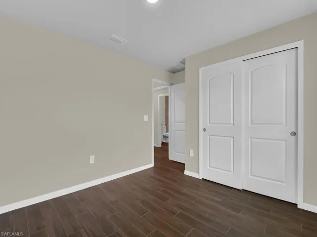Unfurnished bedroom featuring dark hardwood / wood-style floors and a closet
