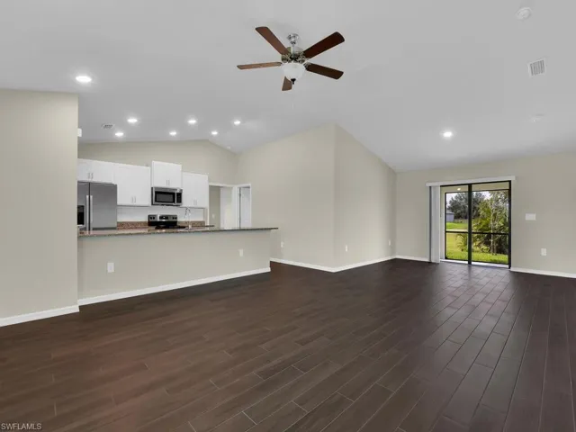 Unfurnished living room featuring sink, high vaulted ceiling, ceiling fan, and dark hardwood / wood-style floors