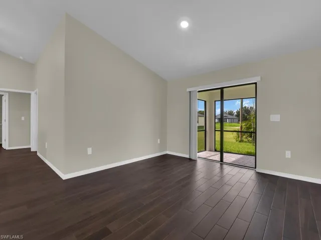 Empty room featuring dark hardwood / wood-style flooring and high vaulted ceiling