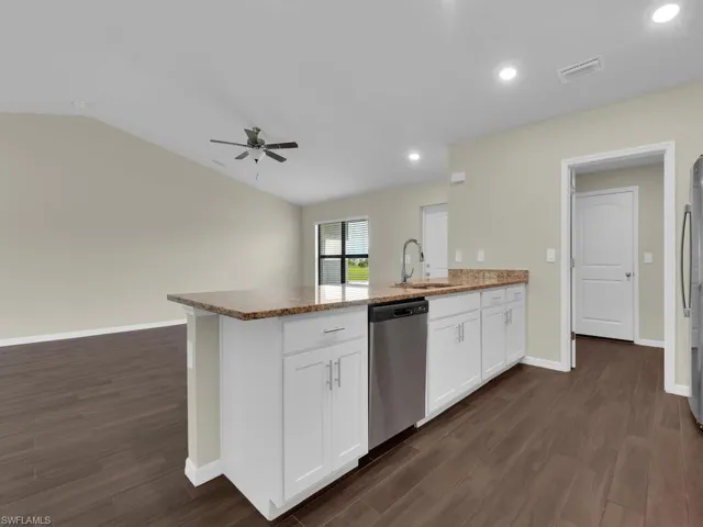 Kitchen featuring kitchen peninsula, dark wood-type flooring, ceiling fan, stainless steel appliances, and sink