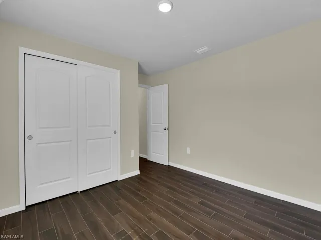 Unfurnished bedroom with a closet and dark wood-type flooring