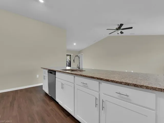 Kitchen with white cabinetry, dark hardwood / wood-style flooring, stainless steel dishwasher, ceiling fan, and sink