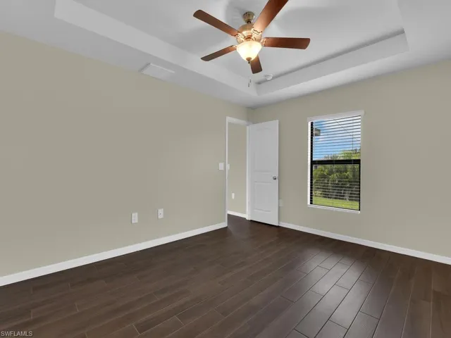 Spare room featuring ceiling fan, dark hardwood / wood-style flooring, and a tray ceiling
