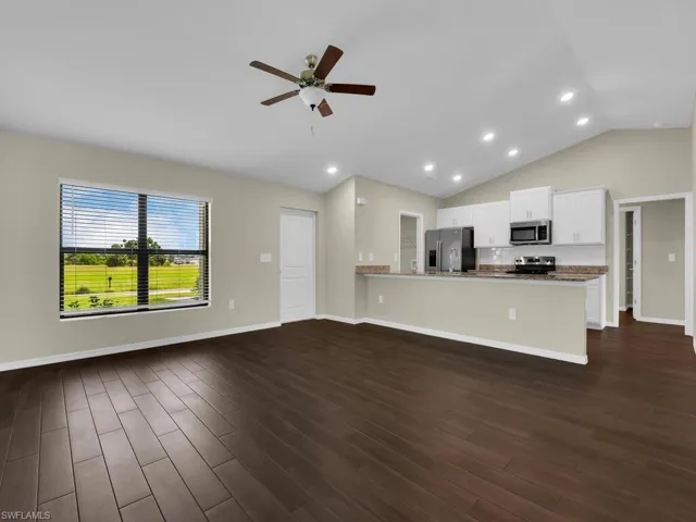 Kitchen with ceiling fan, dark hardwood / wood-style flooring, white cabinets, vaulted ceiling, and appliances with stainless steel finishes