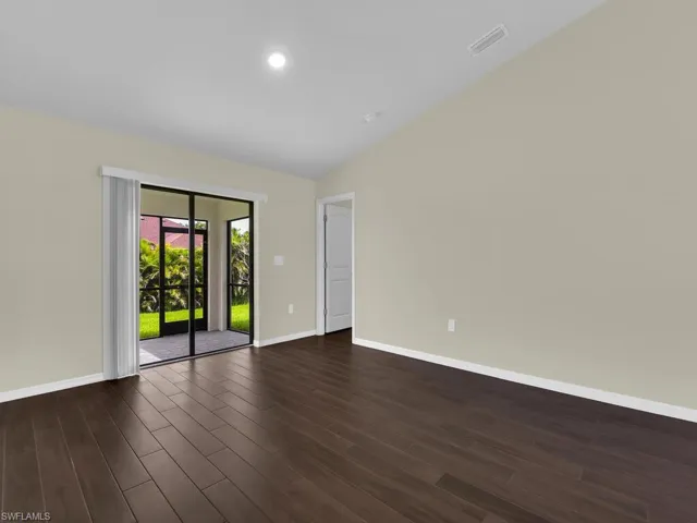 Unfurnished room with dark wood-type flooring and vaulted ceiling