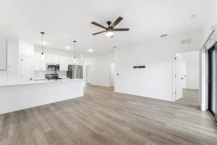 Unfurnished living room featuring light wood-type flooring and ceiling fan