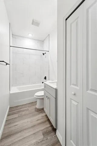 Bathroom featuring vanity,  shower combination, and light wood finished floors