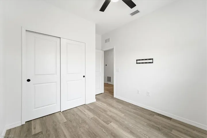 Unfurnished bedroom with ceiling fan, a closet, and light wood finished floors