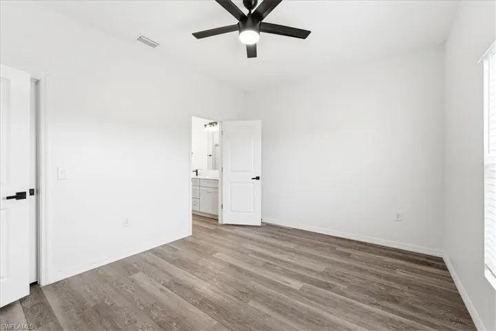 Unfurnished bedroom featuring a ceiling fan, wood finished floors, and ensuite bath