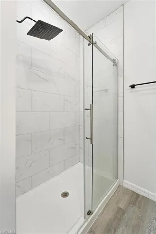 Full bathroom featuring wood finished floors and a stall shower