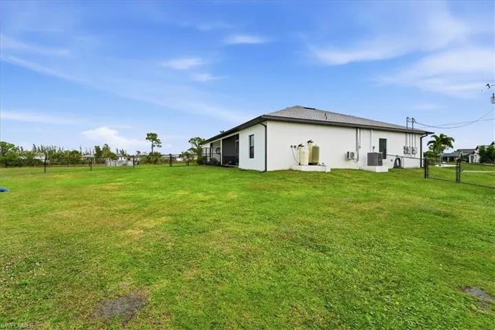 Rear view of property featuring a fenced backyard, stucco siding, and a gate