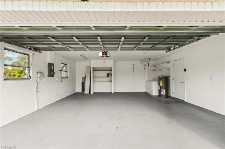 Garage featuring a garage door opener, electric panel, washing machine and clothes dryer, and water heater